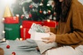 Merry Christmas HandsÃÂ Hands opening christmas gift with red bow on background of christmas tree with lights. in festive room Royalty Free Stock Photo